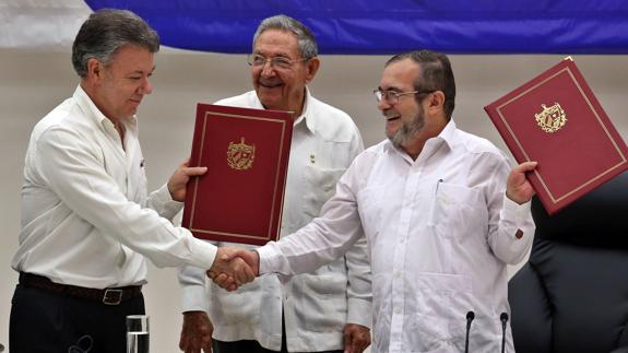 'Timochenko' (d) y el presidente de Colombia, Juan Manuel Santos (i) firman el acuerdo de paz.