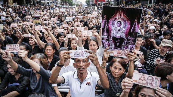 Tailandeses muestran retratos con la imagen del rey Bhumibol Adulyadej.