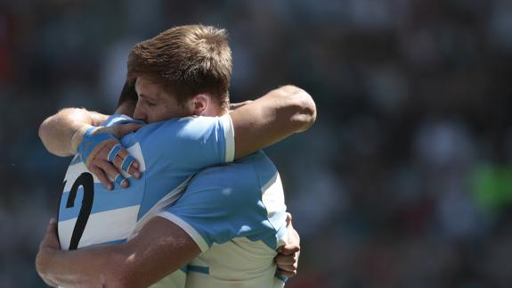 Dos jugadores de la selección argentina de rugby se abrazan. 