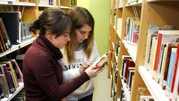 Dos jóvenes consultan un libro.