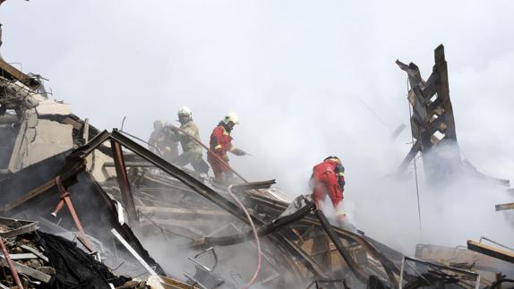 Miembros de los servicios de rescate trabajan en el lugar donde se ha derrumbado un edificio en Teherán.