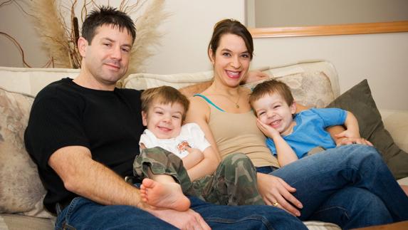 Padres posan con sus dos hijos en el salón de su casa.