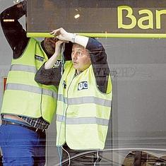 Dos trabajadores colocan un cartel de Bankia en una de sus oficinas.