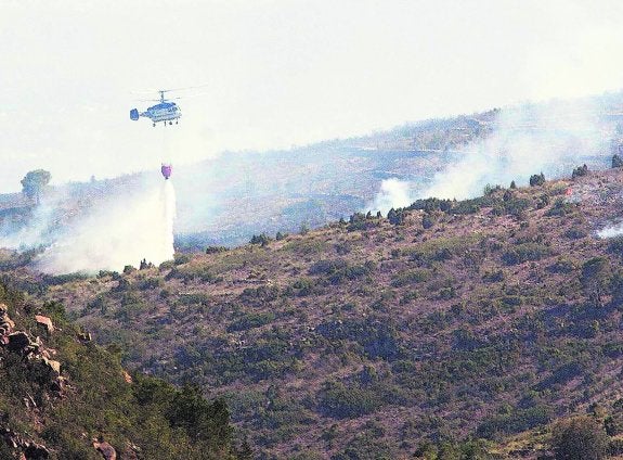 Un helicóptero descarga agua sobre la zona calcinada en Marines.