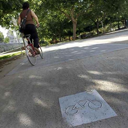 Una mujer circula por el carril bici junto al puente del Real.