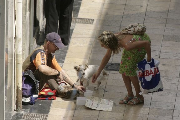 Una chica da una limosna a un hombre en la calle Mayor de Gandia. :: lp