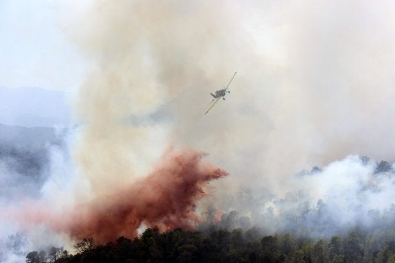 Una avioneta  trabaja en la extinción  del fuego de Domeño. :: efe