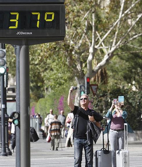 Dos turistas, haciendo fotos a los 37º al sol que marcaba esta mañana un termómetro en Valencia.