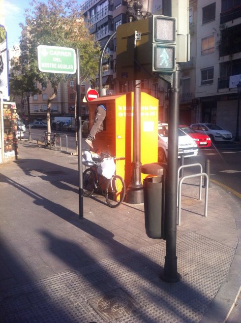 Un hombre introduce medio cuerpo en un contenedor para coger la ropa del interior. :: lp