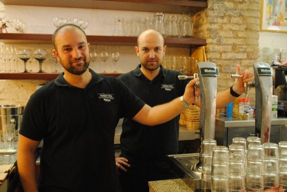 Miguel, a la izquierda, junto a su compañero David ante unos grifos de cerveza Mahou. :: lp