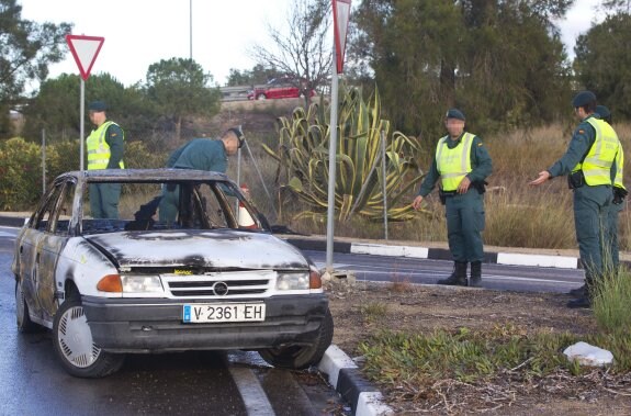 Tres guardias civiles junto al Opel Astra quemado. :: damián torres