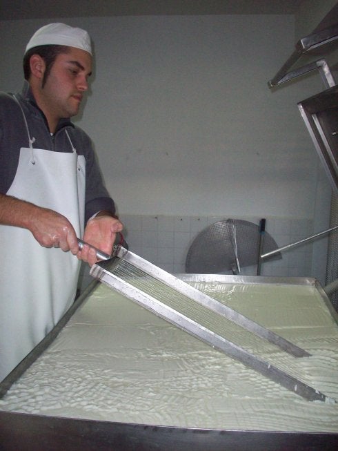 Jesús Calabuig pasa la lira para desmenuzar la cuajada de leche en la cuba de elaboración de queso. :: lp