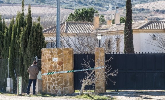 Un hombre se asoma por la verja del chalé donde se produjo el homicidio, ayer, en Villena. :: álex domínguez