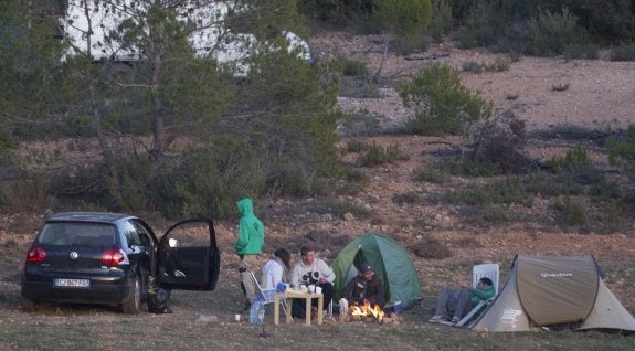 Un grupo de 'ravers' se calienta alrededor de una hoguera junto al aeródromo de Benagéber. :: damián torres