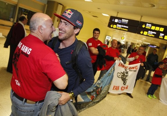 Joan Barreda saluda a un miembro de su club de fans a su llegada ayer al aeropuerto de Manises.