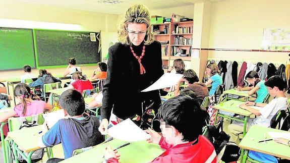 Una maestra reparte pruebas de examen entre sus alumnos.