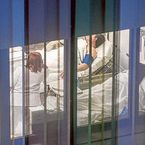 Pacientes entre goteros y una enfermera, en una de las ventanas descubiertas del edificio.