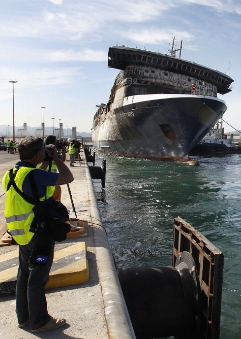 Un fotógrafo toma imágenes del buque incendiado, ayer, segundos antes de atracar en el puerto de Sagunto.  
