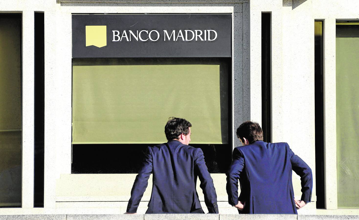 Dos hombres, a la entrada de la sede de Banco Madrid.