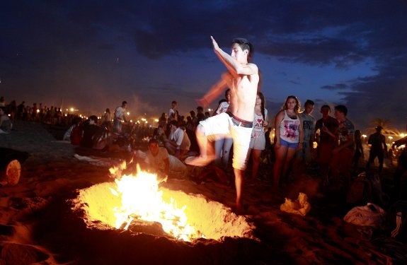 Un clásico. Un joven salta por encima de una hoguera ayer en la Malvarrosa. :: FOTOGRAFÍAS: JESÚS SIGNES