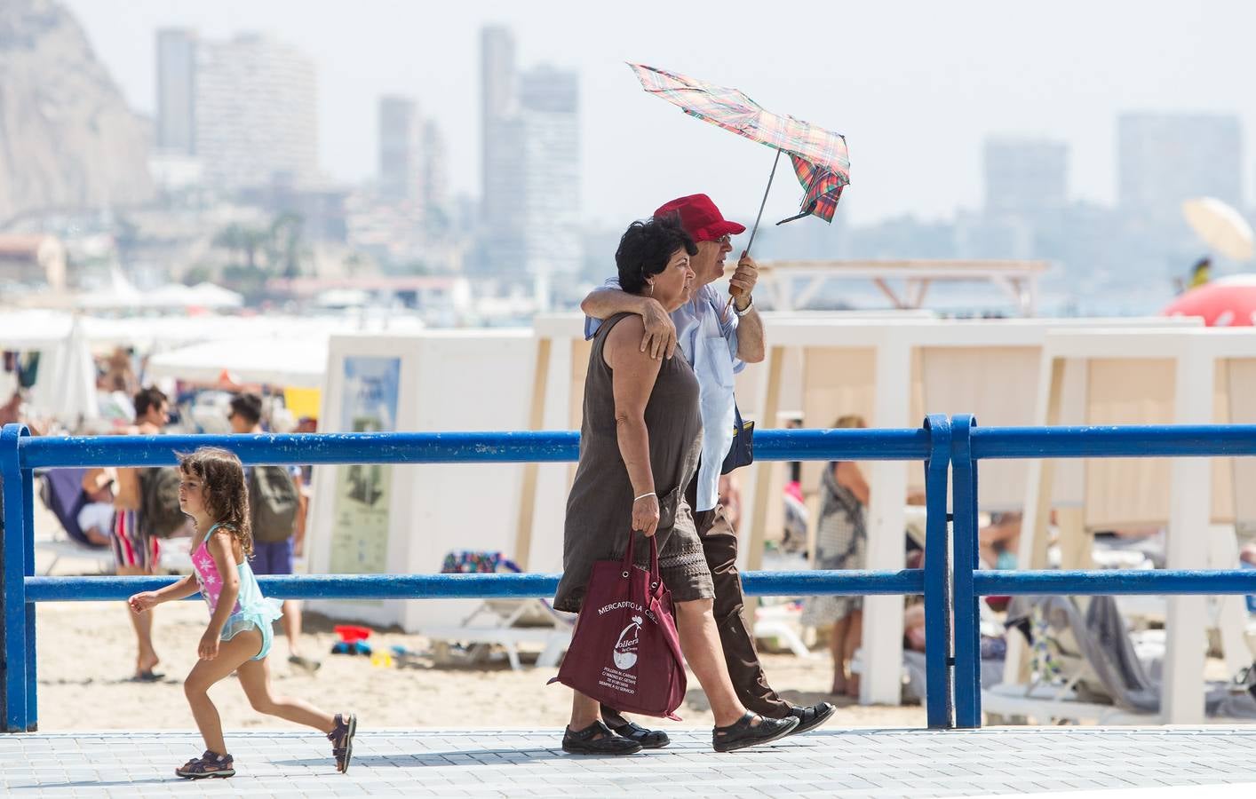 Dos vecinos de Alicante se protegen del calor con un paraguas..