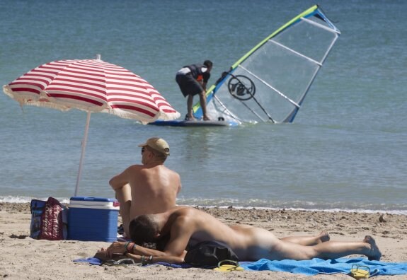 Un aficionado al windsurf practica en la playa, ayer, junto a un grupo de nudistas.  :: damián torres