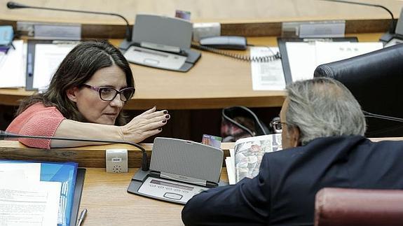 La vicepresidenta del Consell, Mónica Oltra, conversa, durante el pleno de les Corts, con el portavoz socialista Manuel Mata.