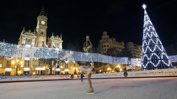 Pista de hielo, árbol de navidad y el Ayuntamiento de Valencia iluminado.