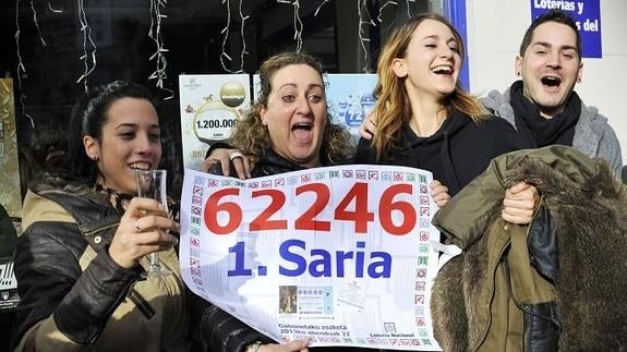 Agraciados con el 'Gordo' de de Navidad sostienen el número agraciado en un despacho de Lotería de Arrasate Mondragón (Guipúzcoa)