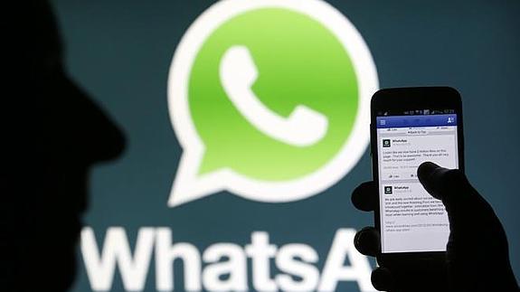 El logo de WhatsApp, junto a un móvil con Facebook abierta, tras la compra de la primera por la segunda.