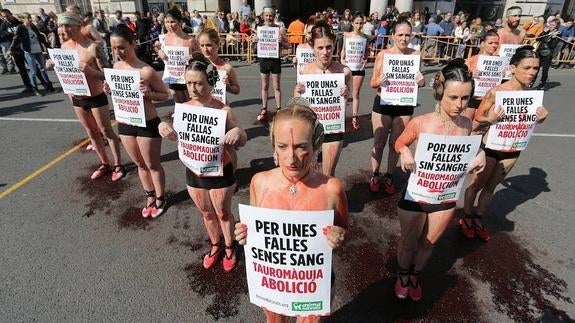 Activistas antitaurinos 'ensangrentados' y ataviados con peinetas, moños y 'espardenyes' protestan contra los toros muertos en Fallas. 