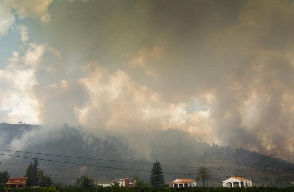 Una densa humareda avanza por las laderas, ayer, en Barraca d'Aigües Vives. :: damián torres