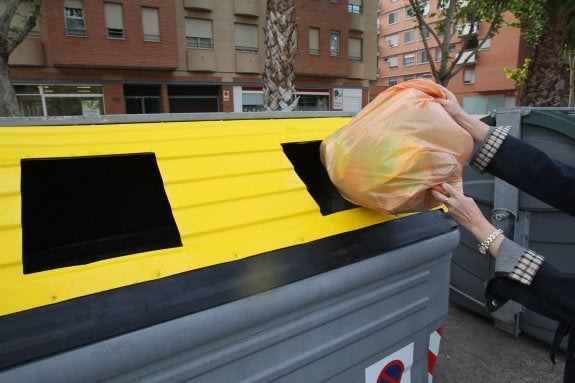 Depositan una bolsa con envases en un contenedor amarillo. :: lp