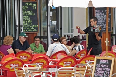 Un camarero atiende a turistas en un restaurante de la playa. :: j. r.