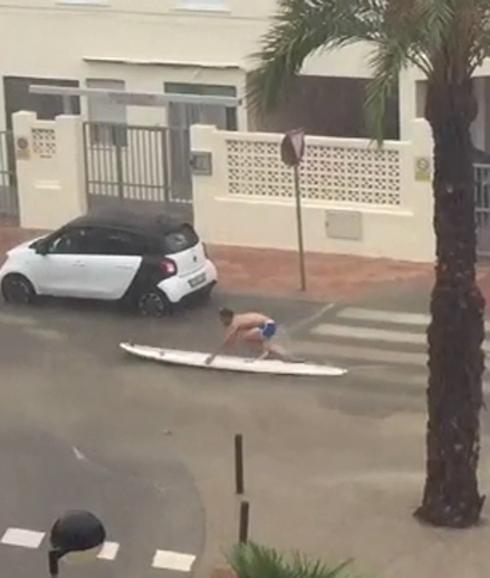 Un joven surfea la lluvia por las calles de Tavernes.