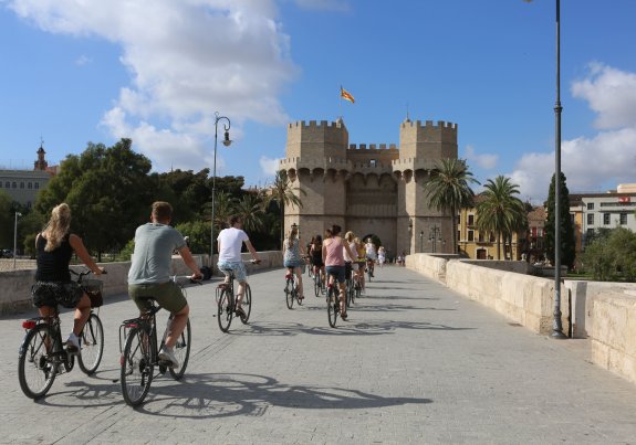 Un grupo de turistas cruza en bici por el puente de Serranos hacia el Carmen. :: carolina amor