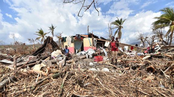 Una familia, junto a una casa destruida en la zona de Los Cayos, en Haití.