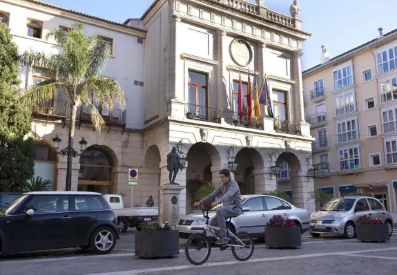 Un joven circula en bicicleta frente al edificio del Ayuntamiento de la ciudad de Gandia. :: lp