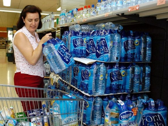 Una mujer compra botellas de agua en un supermercado. :: OLGA LABRADOR