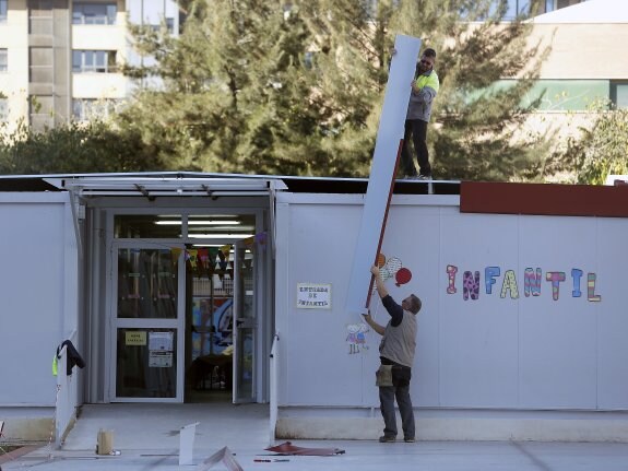 Dos operarios colocando uno de los módulos de la cubierta de Infantil. :: jesús signes