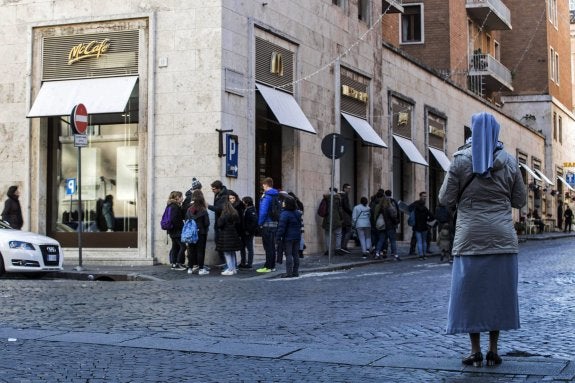 Una monja observa a varios jóvenes a las puertas del polémico McDonald's. :: Massimo Percossi / efe