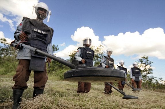 1. Un joven que ha perdido las dos piernas por una bomba aprende a utilizar unas artificiales. 2. Prótesis colgadas en un almacén del centro de rehabilitación de Handicap International. 3. Miembros del Centro de Acción para las Minas de Camboya rastrean el terreno con detectores.  