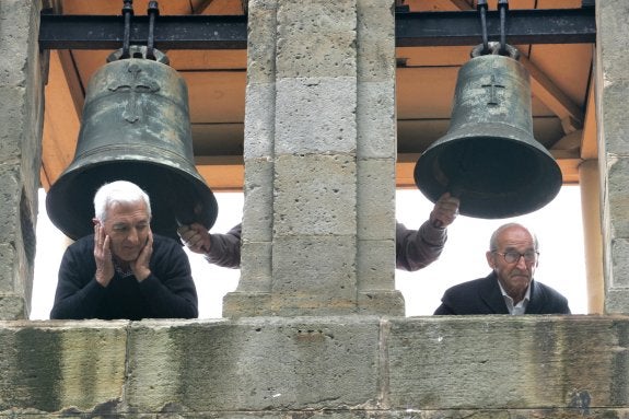 Ruidosa tradición. Dos hombres se asoman por el campanario de San Pedro de Bernueces, en Asturias, mientras tañen las campanas. :: joaquín pañeda