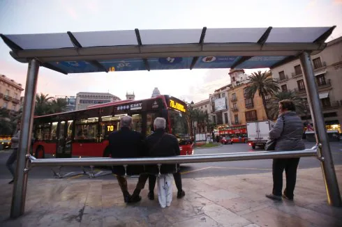 Dos personas esperan al autobús en una parada. :: j. monzo