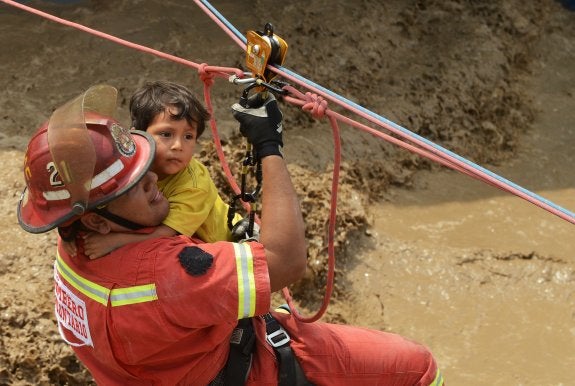 Salvamento. Un bombero rescata a un niño en la localidad de Huachipa, al este de Lima. :: afp