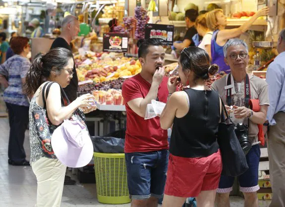 Un grupo de turistas degusta algo de fruta en el Mercado Central, ayer. :: jesús signes