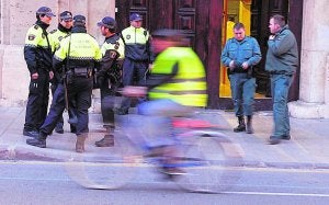 Un ciclista circula por delante de varios agentes de la Policía Local . Txema Rodríguez