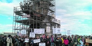 Los manifestantes con pancartas en la estatua de Ripollés, situada en la rotonda de entrada al aeropuerto. ::                             LP