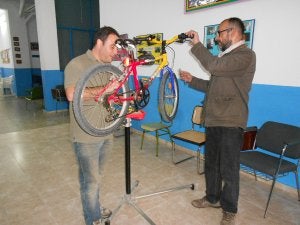 Dos voluntarios de la iniciativa reparan una de las bicicletas donadas al proyecto. ::
A. D.