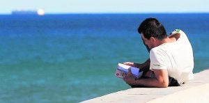 Un vecino aprovecha el buen tiempo para leer un libro frente a la playa de la Malvarrosa. ::                             DAMIÁN TORRES